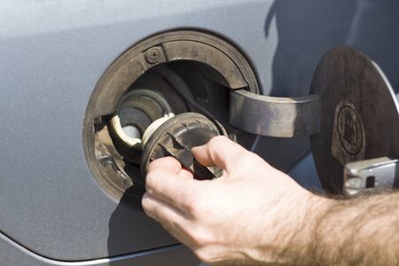 The man unscrews the filler cap in the car.