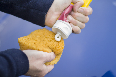 The hands of a mechanic apply a polishing paste on the sponge.の写真素材