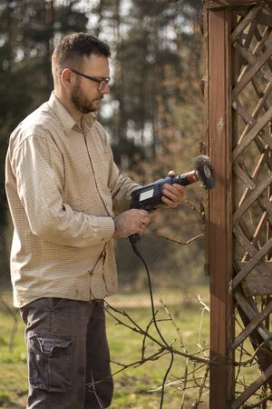 Man with glasses and a flannel shirt during spring gardening. Renovation and maintenance of garden...