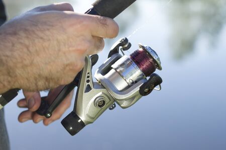 Angler catches fish for spinning. Pulls the fishing line with a spinning-wheel.
