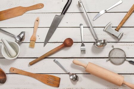Wooden kitchen utensils form a background. They lie on boards painted white.