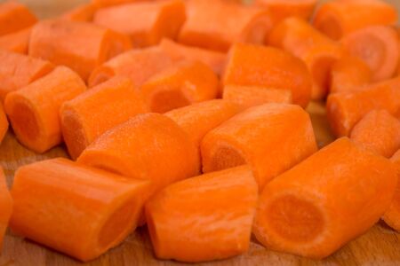 Carrot cut into pieces lies on a wooden chopping board.の写真素材
