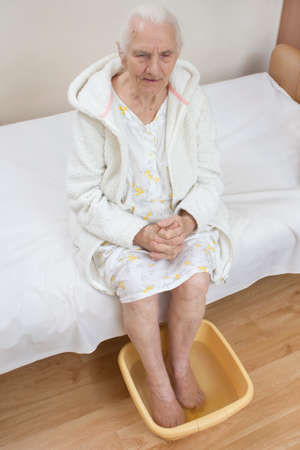 Old woman soaking feet in a bowl of water. The legs of an old woman soak in a bowl of water.の写真素材