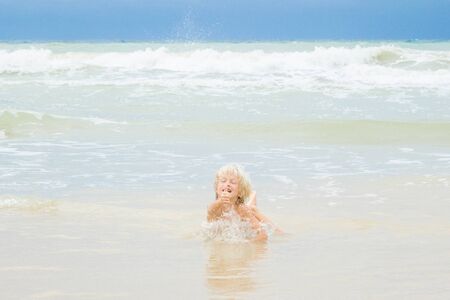 A happy blond boy lies in a water on a beach, Vietnam, Nha-trangの写真素材