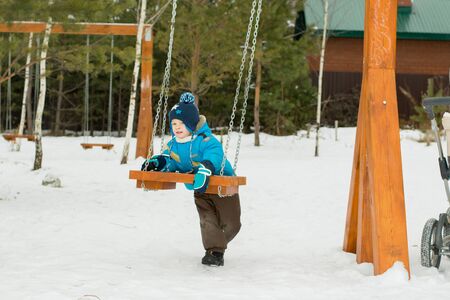 Happy child on swings at a winter parkの写真素材