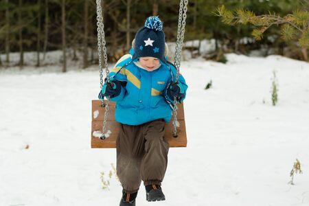 Happy child on swings at a winter parkの写真素材