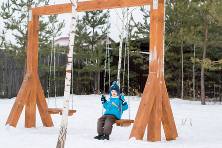 Happy child on swings at a winter parkの写真素材