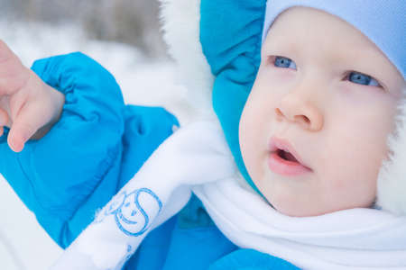 Portrait of a baby with blue eyes in a winter clothes in a parkの写真素材