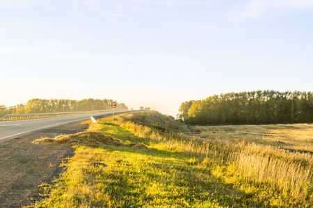 Empty autumn road in golden wheat fieldの写真素材