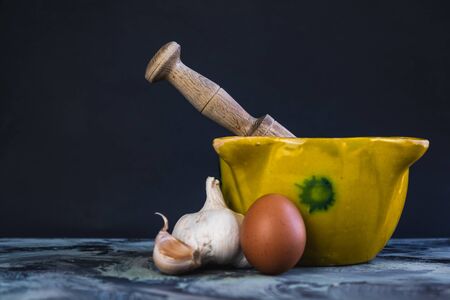 Bowl of garlic and oil sauce with eggs, oil and garlic on black background compositionの写真素材