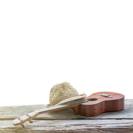 close-up ukulele and hat on wood and white background. over lightの写真素材