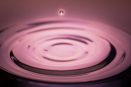 Water drop falling in red backgroundの写真素材