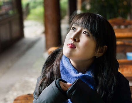 Closeup portrait of a beautiful Chinese girl looking up thinkingの写真素材