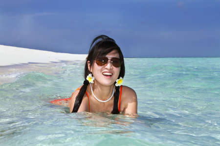A beautiful fashion asian girl playing water in Maldive beach near the ocean in the hot summer