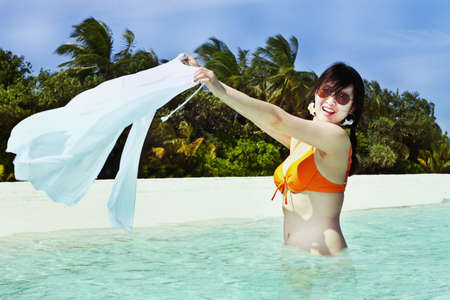 A beautiful fashion asian girl playing water in Maldive beach near the ocean in the hot summerの写真素材