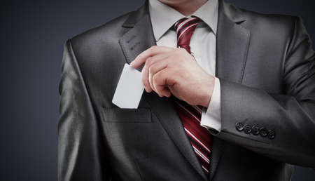 Business man handing a blank business card isolated on gray background High resolution の写真素材