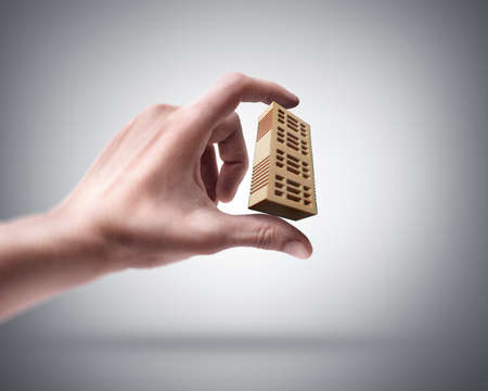 Man's hand holding red brickの写真素材