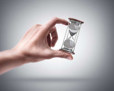 Man's hand holding hourglass