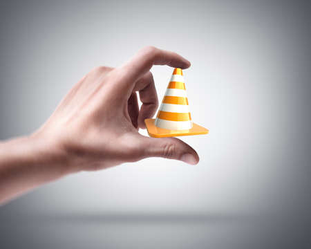 Man's hand holding road coneの写真素材