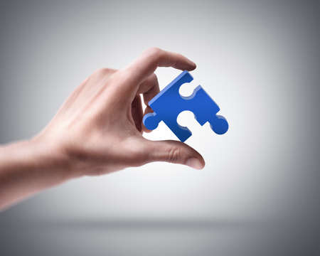 Man's hand holding blue puzzle