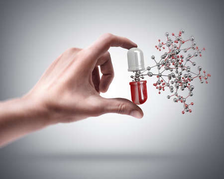 Man's hand holding pill with molecule structureの写真素材
