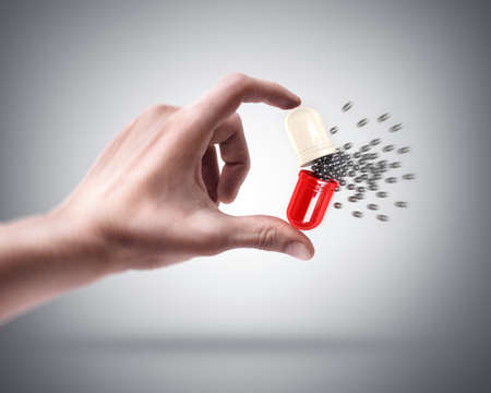 Man's hand holding large capsule and Small nano ballsの写真素材
