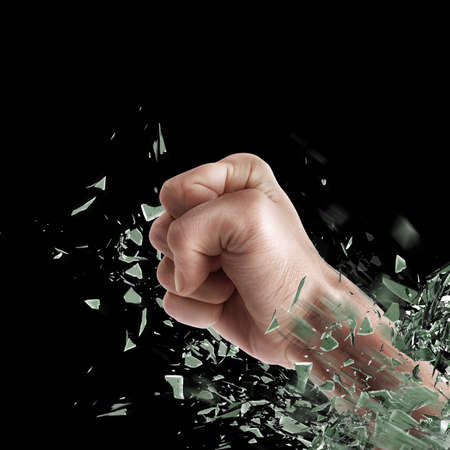 concept. power fist coming out of cracked glass isolated on black background. High resolution の写真素材