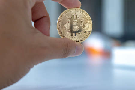 woman is pick and show bitcoin token on table in workplace
