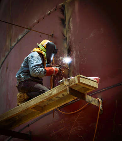 worker with protective mask welding metal and sparksの写真素材