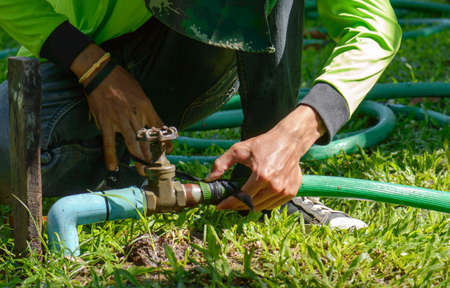 Hand of a man connecting a pipe with a tap in garden