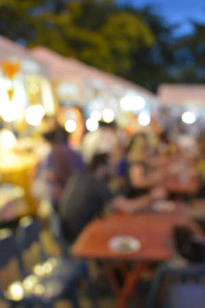 Blurred background of many people eating outside in the streetの写真素材