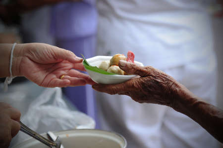 Hand give food to hands of a beggarの写真素材