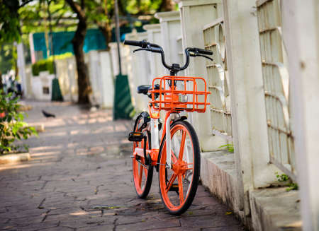 orange bicycle close to fenceの写真素材