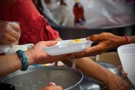 Rich people give food to the poor. starvation conceptの写真素材