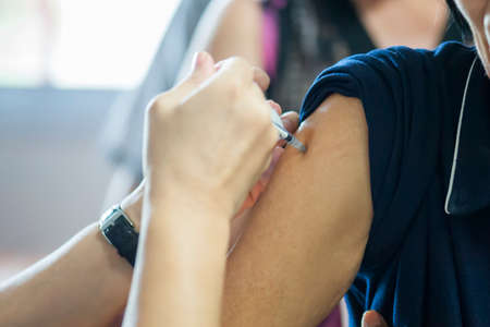 Getting flu vaccines from a doctor with an injection in the arm.