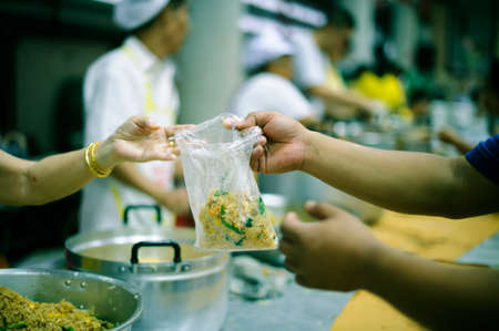 The hands of beggars receive donated food as a share in society : the concept of hungerの写真素材