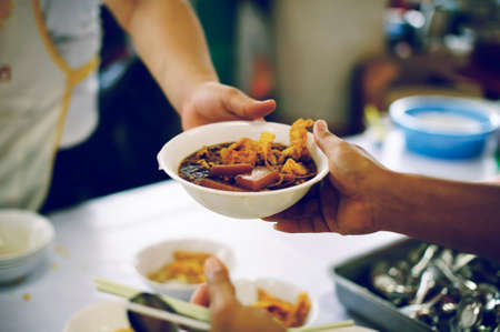 Donating food to beggars to alleviate hunger : the concept of sharing help to fellow human beings in society.の写真素材