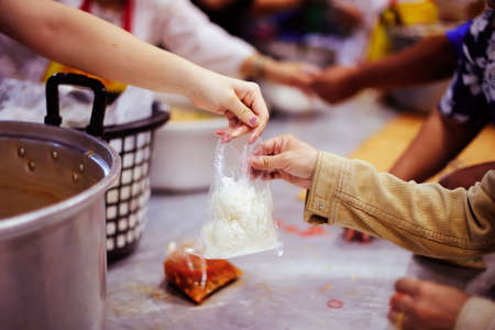 The hands of refugees have been aided by charity food to alleviate hunger : the concept of humanitarianism.の写真素材
