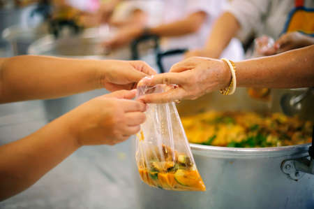 Homeless people pick up charity food from the food donors in society : concept homelessnessの写真素材