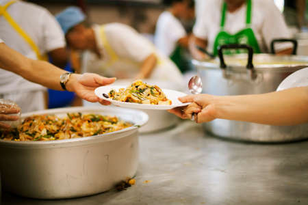 The nomadic hand received food donations from the hands of volunteers: the concept of sharing the givingの写真素材