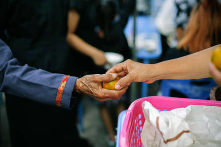 Food donation: The hands of the hungry are receiving food from the service provider.の写真素材