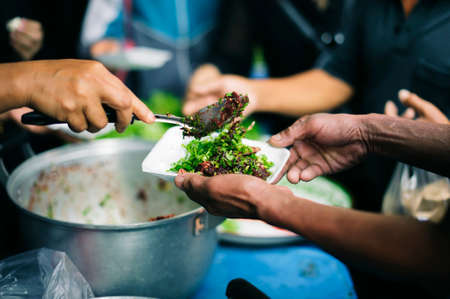 Volunteers serving charity food to the poor: the concept of hungerの写真素材
