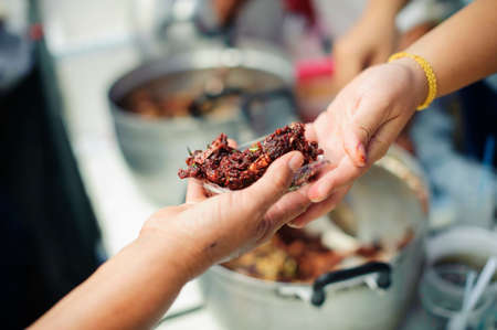 Volunteers provide food for beggars : Concepts Feeding and help : The hands of the rich give food to the hands of the poorの写真素材