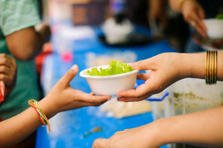 Volunteers provide food for beggars : Concepts Feeding and help : The hands of the rich give food to the hands of the poorの写真素材