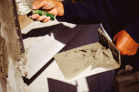 Workers are using a trowel to decorate the cement pillars into a beautiful ridge.の写真素材