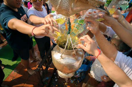 LAMPHUN, THAILAND - MAY 18, 2019 : People together pour water together to bathe Phra That Chedi Hariphunchai in Lamphun, Thailand.のeditorial素材