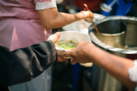 Helping People With Hunger With Kindness : the concept of life problems, hunger in society : concept of charity food for the poor : Hand-feeding to the needy in societyの写真素材