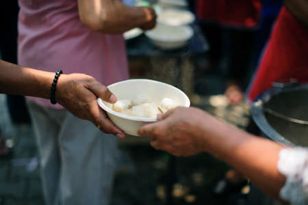 Hand-feeding to the needy in society : Concept of Feeding : Volunteers give food to the poor :...