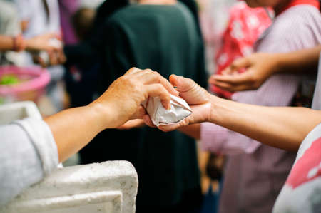 Volunteers give food to the poor : donating food is helping human friends in society : Helping People With Hunger With Kindness : the concept of life problems, hunger in societyの写真素材