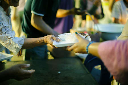 Concept of Feeding : Volunteers give food to the poor : donating food is helping human friends in society : Helping People With Hunger With Kindness : the concept of life problems, hunger in societyの写真素材